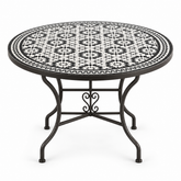 Round zellige mosaic dining table with bold black and white star-and-floral tile pattern and black wrought iron scrolled base