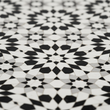 Close-up macro of bold black and white star-and-floral zellige mosaic tile pattern