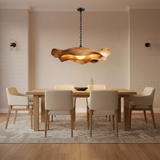 Sculptural wooden pendant light glowing above a modern dining table