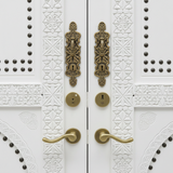 Close-up of ornate brass-tone handles and carved white woodwork
