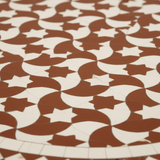 Close-up macro of terracotta red-brown and cream interlocking crescent and star tessellating zellige mosaic pattern with fine cream diamond border
