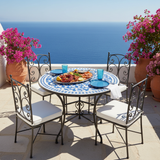 Sky blue and white pinwheel zellige mosaic dining table on a sun-drenched whitewashed Greek island coastal terrace with azure sea view bougainvillea blue ceramic plates and fresh seafood