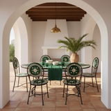 Emerald green zellige oval mosaic dining table in a bright Mediterranean villa interior with white plaster walls dark wooden beams terracotta floor ivory linen chairs and tropical palm