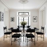 Black and white checkerboard zellige oval mosaic dining table in a chic Parisian apartment dining room with plaster moldings black steel windows white roses black leather chairs and crystal glassware