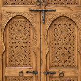 Close-up of forged iron ring pulls, sliding bolt latch, and carved horseshoe arches