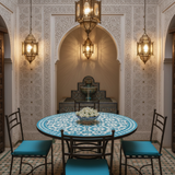 Turquoise zellige mosaic dining table in a serene Moroccan riad interior with carved plaster walls brass lanterns and silk cushioned chairs