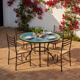 Turquoise and blue zellige mosaic dining table on a sun-drenched Andalusian courtyard patio with bougainvillea and woven rush iron chairs