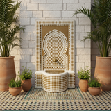 Moroccan mosaic fountain mounted in whitewashed riad courtyard with water flowing