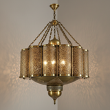 Three-quarter detail of an antique brass Moroccan chandelier glowing through its filigree panels